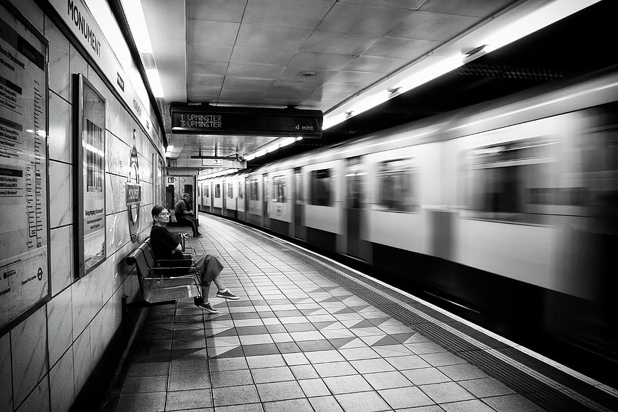 Woman waiting on London Underground platform with passing train
