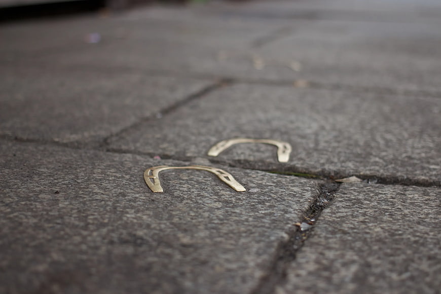 Two golden horseshoes on gray stone pavement