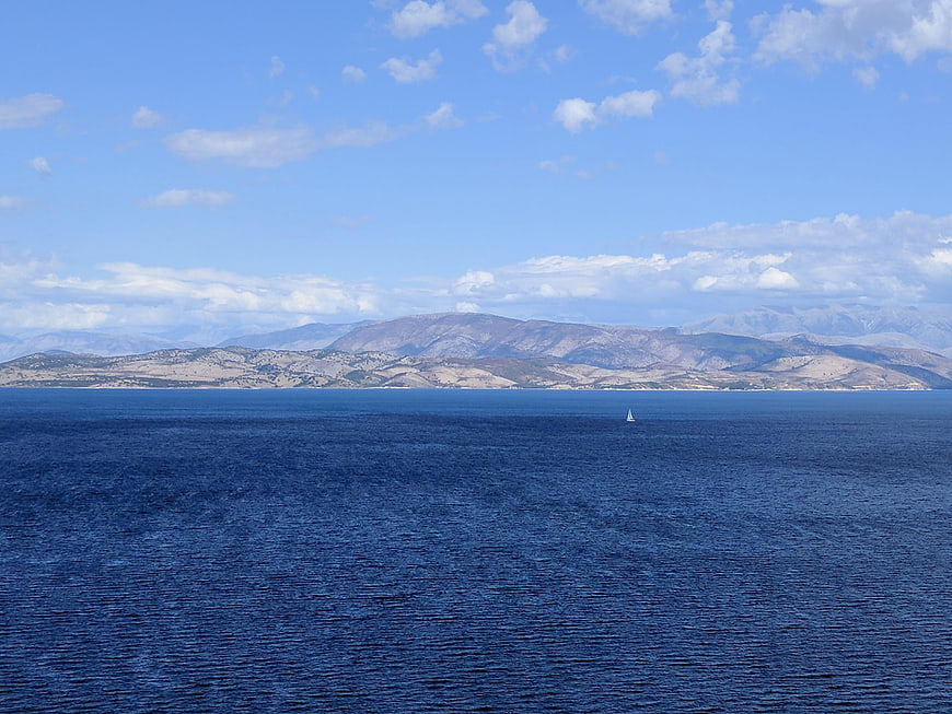 Serene seascape with distant mountains and sailboat