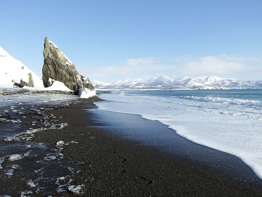 Winter landscape of black sand beach with snow and ocean waves
