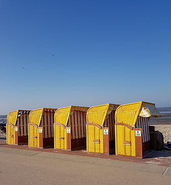 Row of yellow beach huts on sandy shore