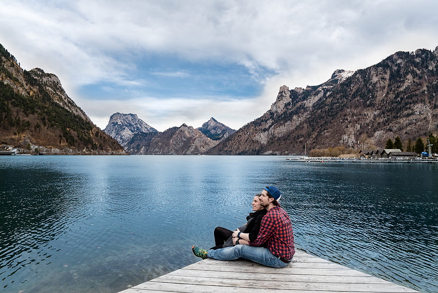 Couple sitting on wooden pier by mountain lake