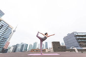 Woman doing yoga on city rooftop with skyline