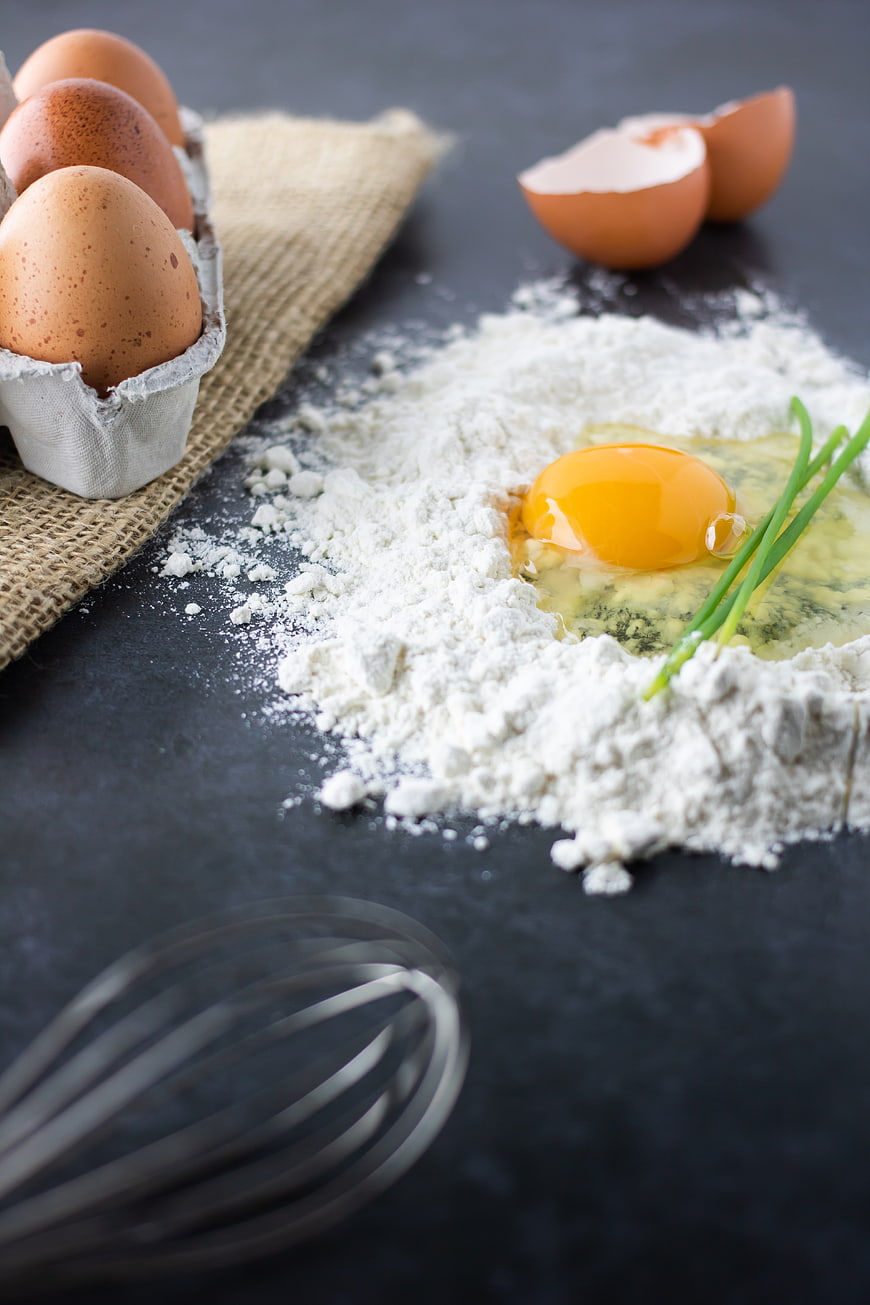 Fresh eggs and flour on dark slate for baking