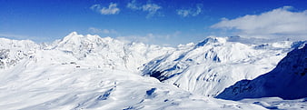 Panoramic View of Snow-Covered Mountain Peaks Under Blue Sky