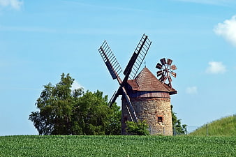 Historic Stone Windmill in Green Field Under Blue Sky