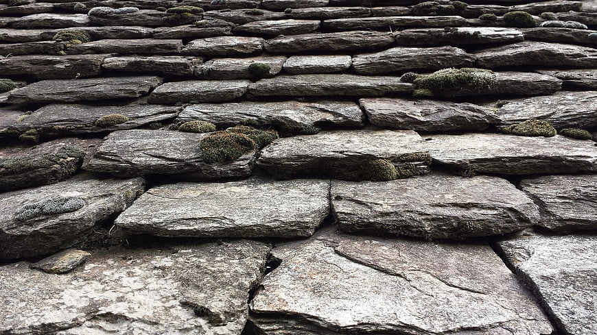 Close-up of weathered slate roof tiles with moss growth