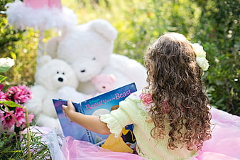 Little girl reading Beauty and the Beast with teddy bears