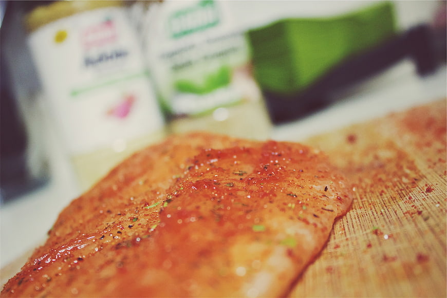 Seasoned raw salmon fillet on wooden cutting board