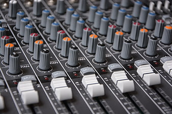Close-up of professional audio mixing console with faders and knobs