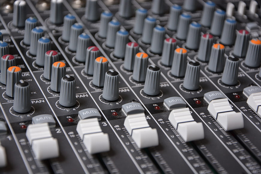Close-up of professional audio mixing console with faders and knobs