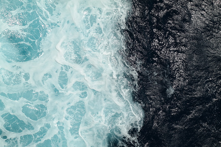 Aerial View of Turquoise Sea Waves Crashing on Dark Rocks