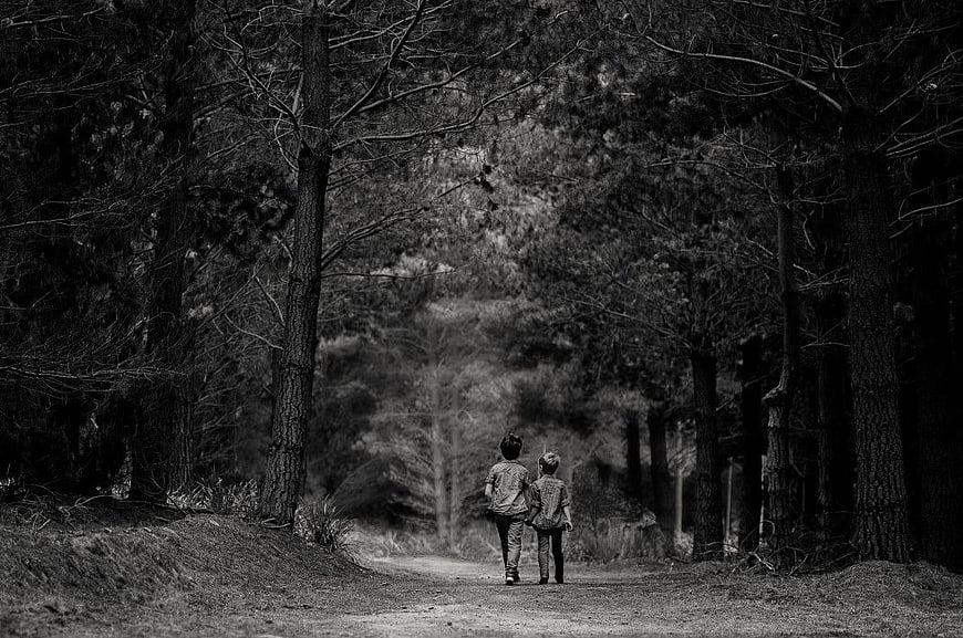 Two Boys Walking Away on a Forest Path in Black and White
