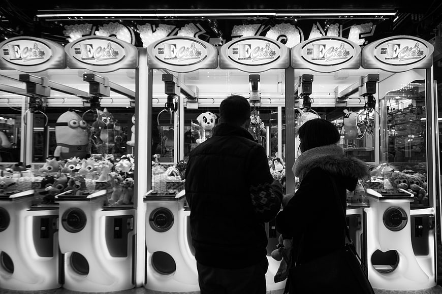 Couple Playing Claw Machines in Black and White