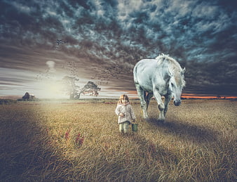 Child and white horse walking in a dramatic rural field
