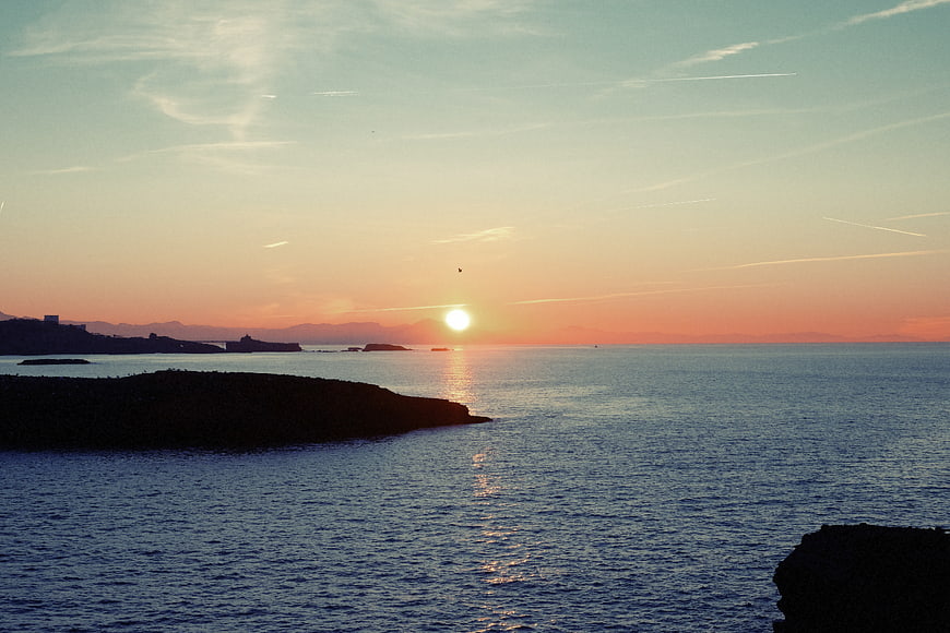 Serene Sunset Over Ocean with Silhouetted Coastline and Islands