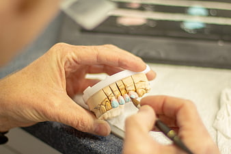 Dental Technician Applying Glaze to Ceramic Teeth Model