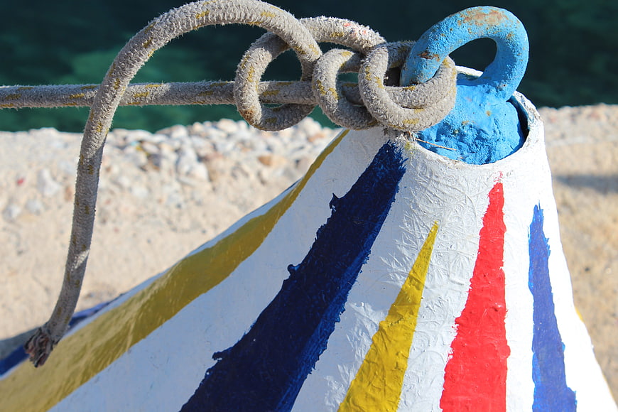 Colorful striped buoy with rope knot on sunny beach