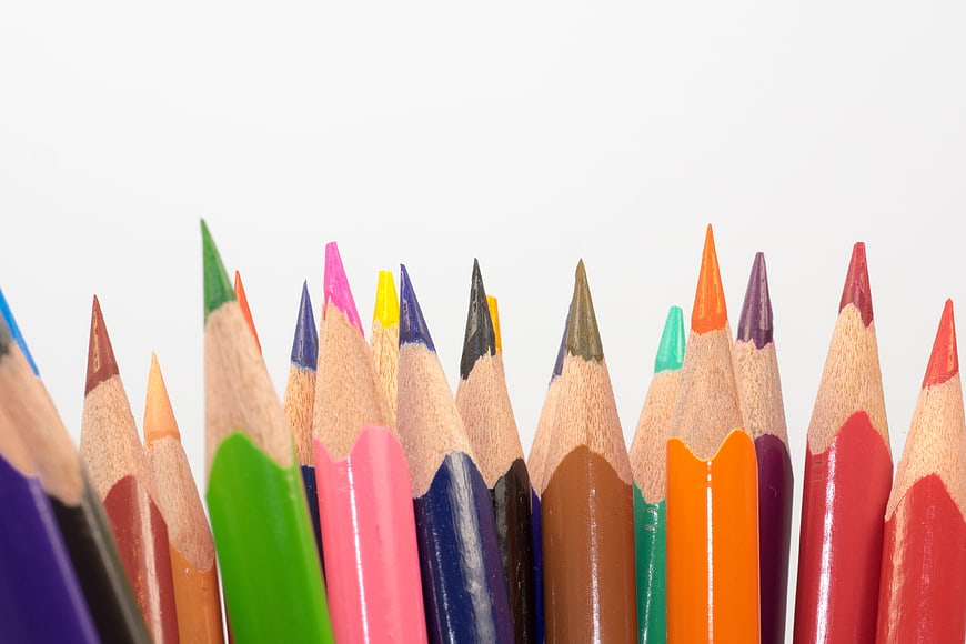 Close-up row of colorful sharpened wooden pencils on white background
