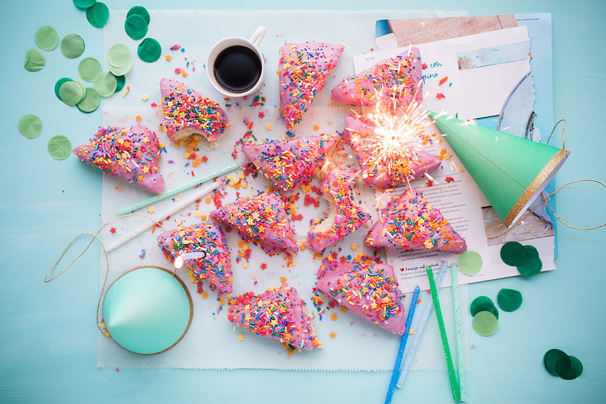 Flat lay of pink cake slices with sprinkles and party decorations