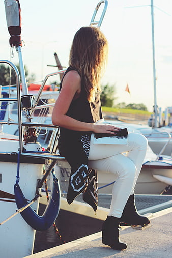 Woman sitting on boat dock in white pants