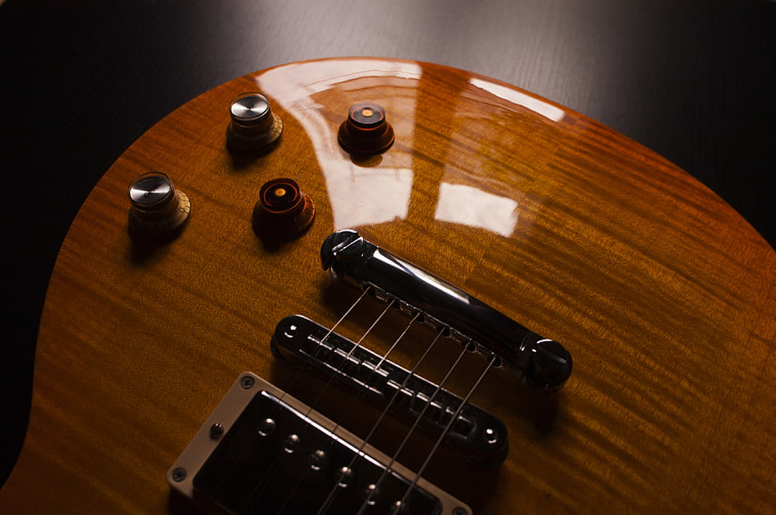 Close-up of glossy brown electric guitar body with knobs and bridge