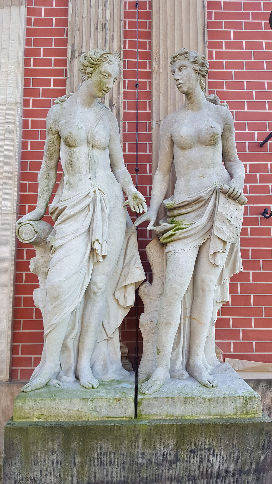 Classical Stone Statues of Women on Red Brick Building