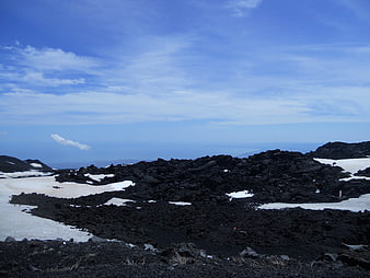 Volcanic landscape with black lava rocks and snow patches