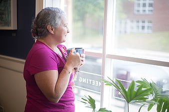 Senior woman drinking coffee while looking out window