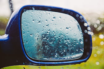 Close-up of blue car side mirror with raindrops