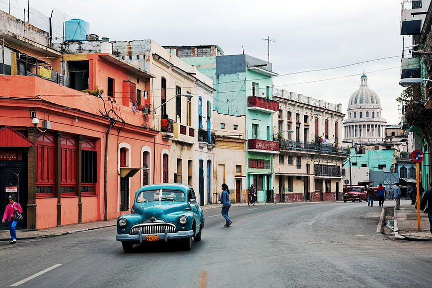 Vintage turquoise classic car driving on Havana street with Capitolio