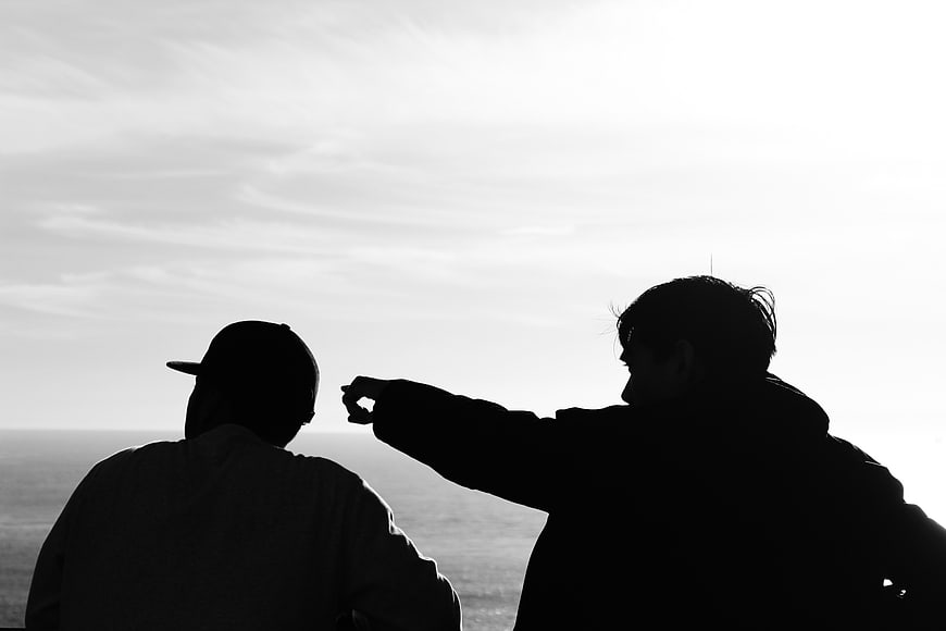 Silhouette of Two Men Pointing at Ocean Horizon