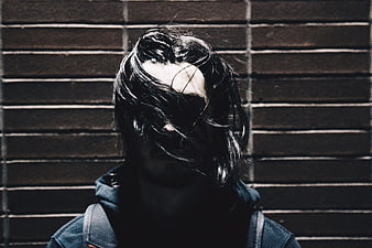 Moody Portrait of Person with Hair Covering Face Against Brick Wall