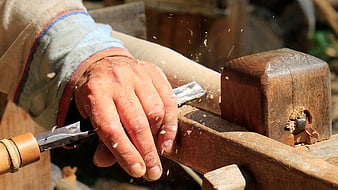 Close-up of a craftsman's hands carving wood with a chisel