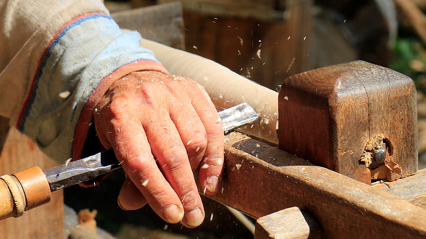 Close-up of a craftsman's hands carving wood with a chisel