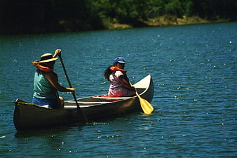 Two women paddling a canoe on a sunny lake