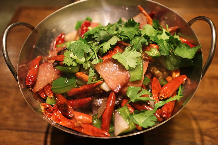 Spicy stir-fry dish with chilies and cilantro in metal wok