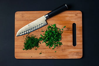 Chopped parsley and dill on wooden cutting board with knife