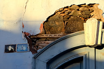 Dilapidated wall with exposed stone and blue door frame