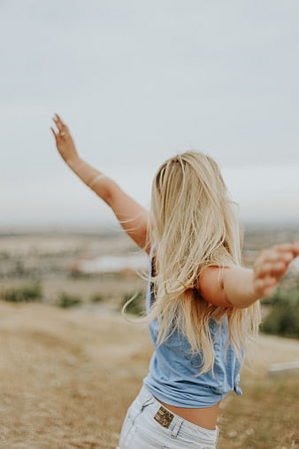 Blonde woman with arms raised enjoying freedom in nature
