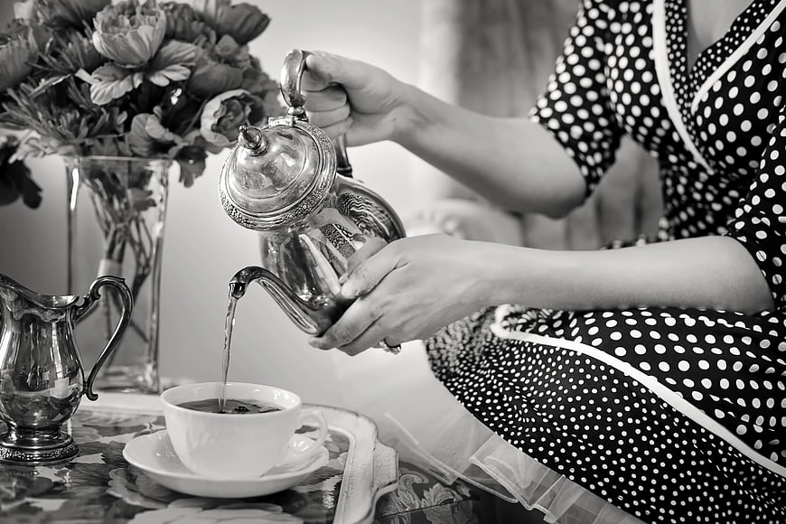 Woman pouring tea from vintage silver teapot