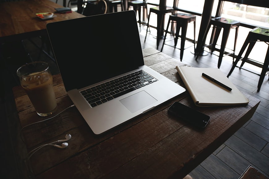Laptop Workspace with Coffee and Notebook on Wooden Table