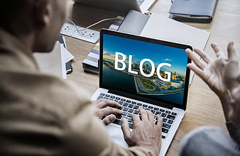 Man Typing On Laptop With Blog Text Displayed On Screen