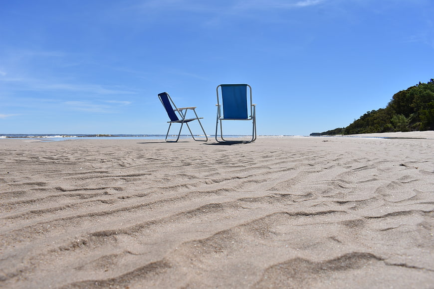 Two Blue Beach Chairs on Sandy Shore Under Blue Sky