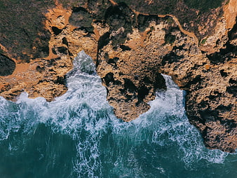 Aerial View of Turquoise Waves Crashing Against Rocky Coastline