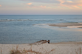 Serene beach landscape with wooden pier and calm ocean at sunset