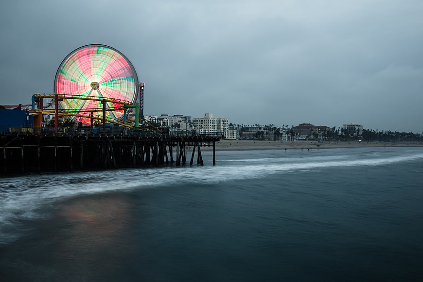 Colorful Ferris Wheel on Pier Against Moody Ocean Sky