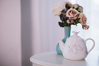 White ceramic teapot with roses on a table