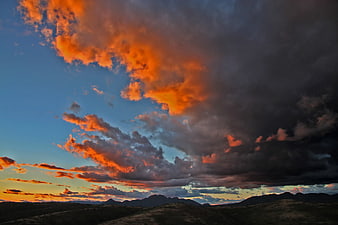 Dramatic sunset with fiery orange clouds over dark mountain landscape