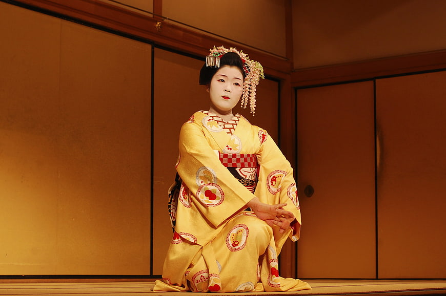 Japanese Geisha in Traditional Yellow Kimono Seated on Stage